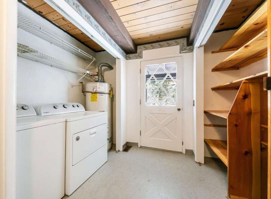 Step into this charming laundry room, complete with a washer and dryer, and a water heater.