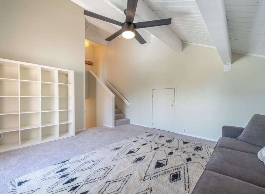 Step into this inviting living space featuring a modern ceiling fan and a stylish rug.