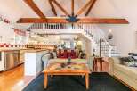 This charming cabin-style home boasts a cozy living area with a loft and exposed wooden beams, creating a warm and inviting atmosphere.