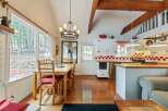 This charming kitchen and dining area boasts a cozy atmosphere with its wooden floors, exposed beams, and a stylish chandelier.