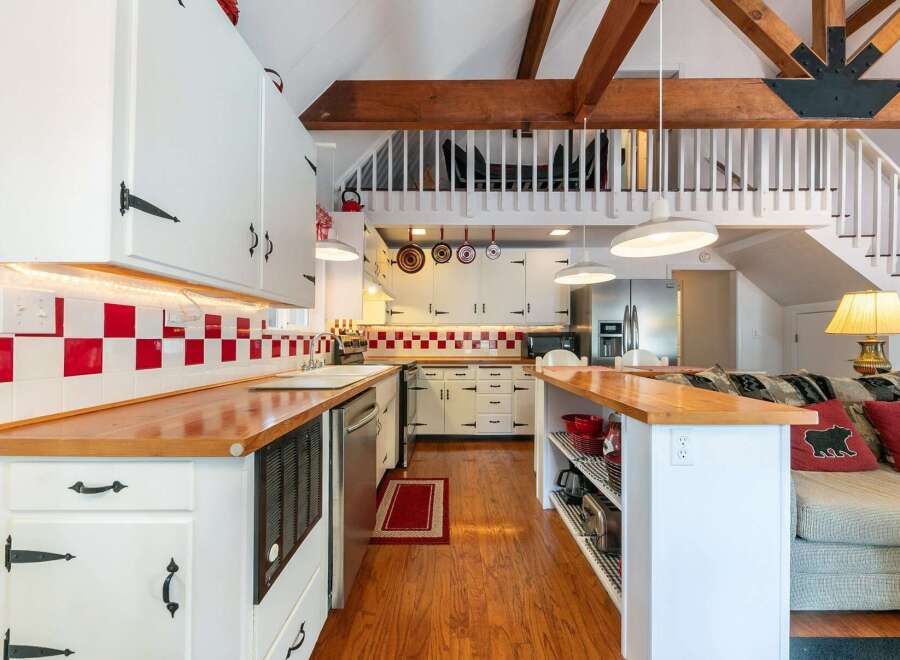Step into this charming kitchen, featuring a unique red and white checkered backsplash and warm wooden countertops.
