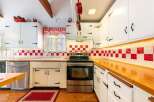 Step into this charming kitchen, featuring a classic design with white cabinetry and a striking red and white checkered backsplash.