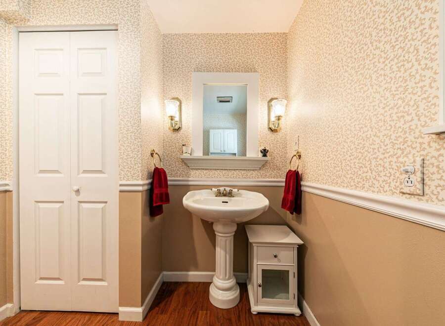 This charming powder room features a pedestal sink, elegant lighting, and a stylish mirror.