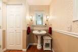 This charming powder room features a pedestal sink, elegant lighting, and a stylish mirror.