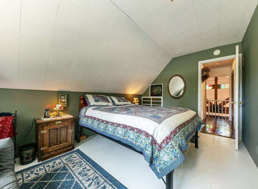 This charming bedroom features a cozy bed with a floral quilt, perfect for a relaxing retreat.