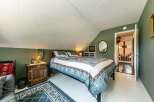 This charming bedroom features a cozy bed with a floral quilt, perfect for a relaxing retreat.