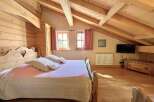 Discover the charm of this cozy bedroom featuring a rustic wooden bed frame and exposed beams, creating a warm and inviting atmosphere.