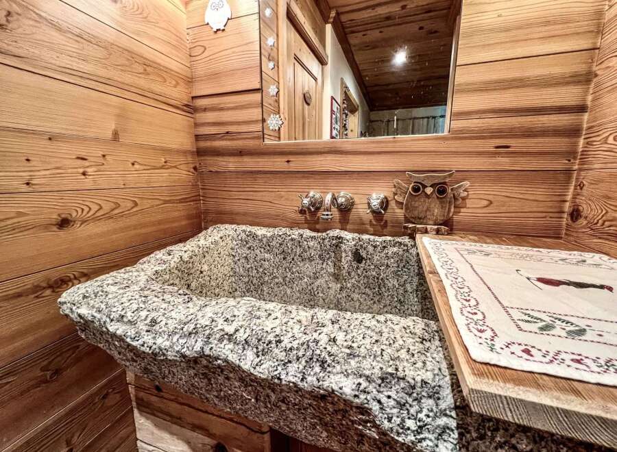 Experience rustic charm in this unique bathroom featuring a stunning stone sink.