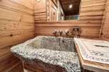 Experience rustic charm in this unique bathroom featuring a stunning stone sink.