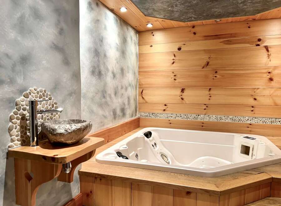 Indulge in luxury with this stunning bathroom featuring a jacuzzi tub and a unique stone sink.