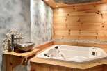 Indulge in luxury with this stunning bathroom featuring a jacuzzi tub and a unique stone sink.
