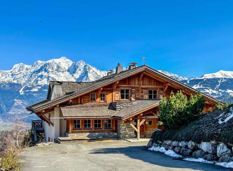 Discover the charm of this stunning wooden chalet nestled against a backdrop of majestic snow-capped mountains.