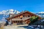Discover the charm of this stunning wooden chalet nestled against a backdrop of majestic snow-capped mountains.