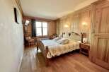 This charming bedroom features a cozy wooden bed frame with a heart-shaped cutout, complemented by matching wooden paneling and flooring.