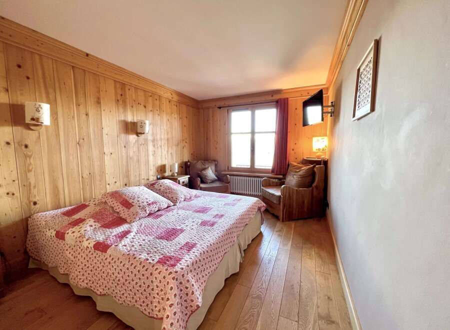 This charming bedroom features warm wooden paneling and a cozy atmosphere, perfect for a relaxing retreat.