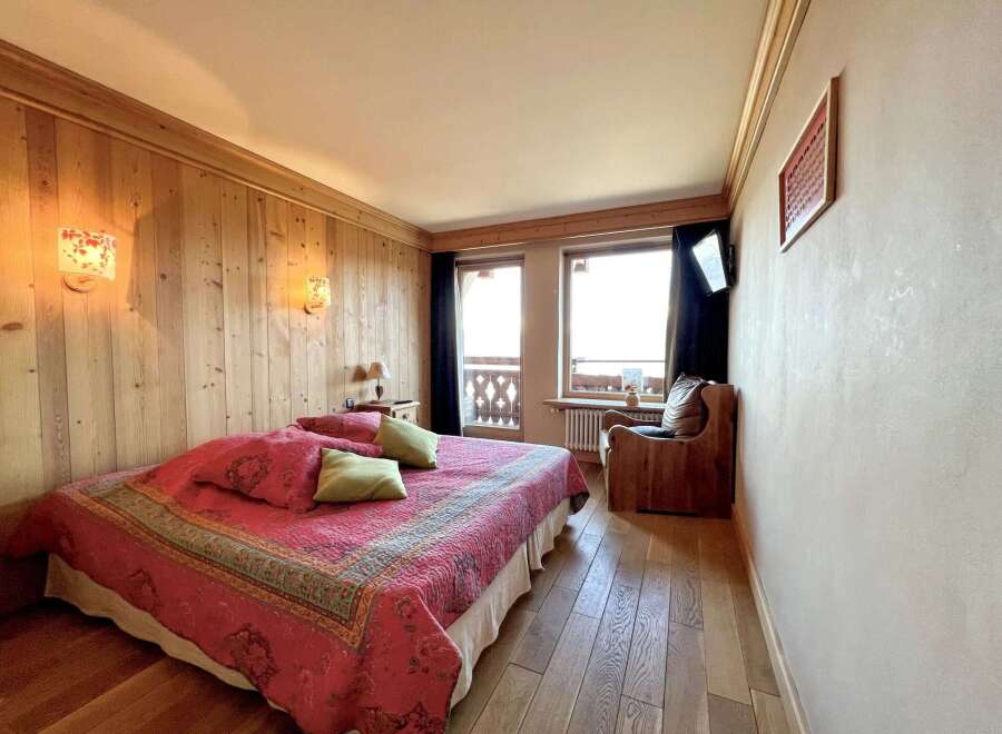Experience the charm of this cozy bedroom featuring a comfortable bed with a vibrant red quilt and decorative pillows.