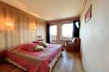 Experience the charm of this cozy bedroom featuring a comfortable bed with a vibrant red quilt and decorative pillows.