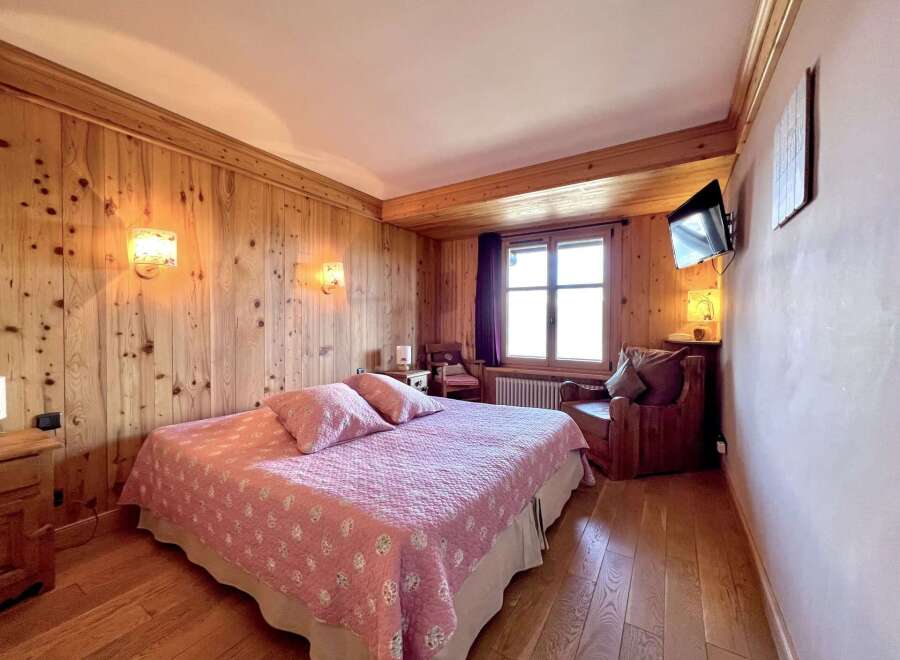 Cozy bedroom with wooden paneling and a comfortable bed.