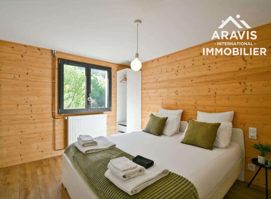 Discover the charm of this cozy bedroom, featuring warm wooden walls and a comfortable bed.