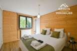 Discover the charm of this cozy bedroom, featuring warm wooden walls and a comfortable bed.
