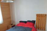 This cozy bedroom features a comfortable bed with a stylish red and gray comforter.