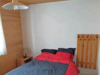 This cozy bedroom features a comfortable bed with a stylish red and gray comforter.