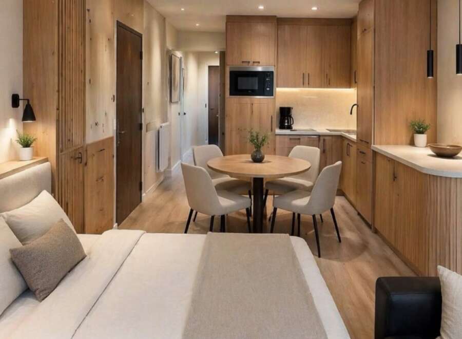 Discover modern living in this beautifully designed studio apartment, featuring a cozy sleeping area and a fully equipped kitchenette with sleek wooden cabinetry.