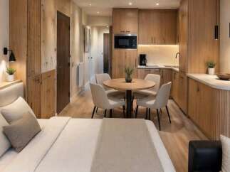 Discover modern living in this beautifully designed studio apartment, featuring a cozy sleeping area and a fully equipped kitchenette with sleek wooden cabinetry.