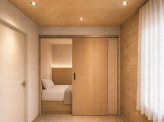 Discover this serene bedroom featuring a cozy bed with a plush duvet and a neutral throw, nestled within a cleverly designed alcove.