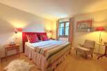 This cozy bedroom features a comfortable bed with a vibrant red headboard and decorative pillows, creating a warm and inviting atmosphere.