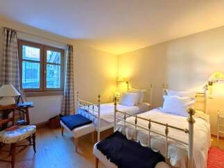 This charming bedroom features two twin beds with elegant white frames, perfect for guests or a cozy shared space.