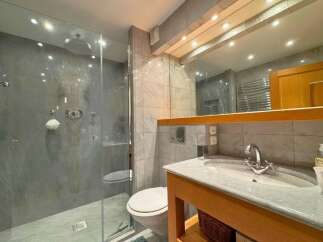 This stunning bathroom features a luxurious walk-in shower with a rain showerhead and elegant marble-like tiles.