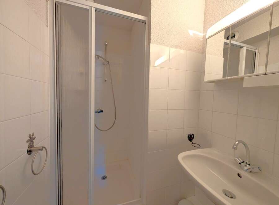 Step into a clean and modern bathroom, featuring a sleek shower enclosure and pristine white tiling.