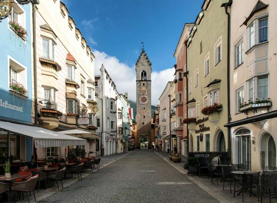 Explore the charm of this historic European town, featuring colorful buildings and a cobblestone street.
