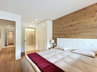 This stunning bedroom boasts a modern design with a touch of warmth, featuring a beautiful wooden accent wall.