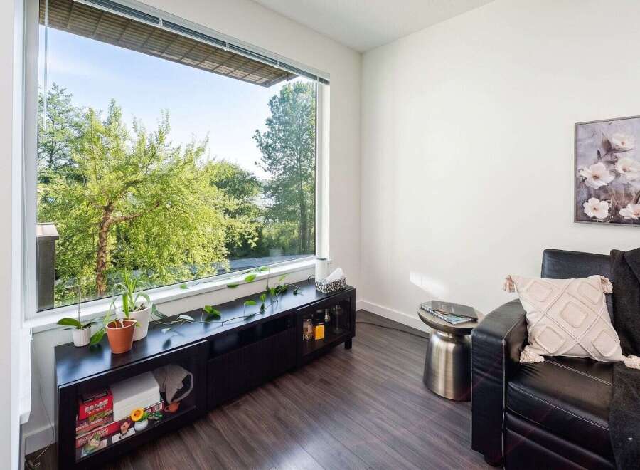 This stunning living space boasts a modern design with a large window offering breathtaking views of lush greenery.