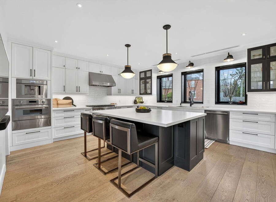 This stunning kitchen boasts a modern design with sleek white cabinetry and a contrasting dark island.