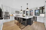 This stunning kitchen boasts a modern design with sleek white cabinetry and a contrasting dark island.