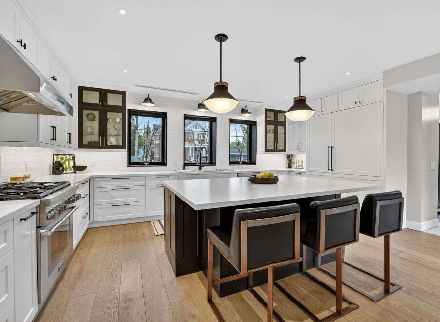 This stunning kitchen boasts a modern design with sleek white cabinetry, complemented by dark accents and elegant pendant lighting.