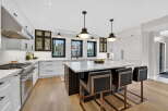 This stunning kitchen boasts a modern design with sleek white cabinetry, complemented by dark accents and elegant pendant lighting.