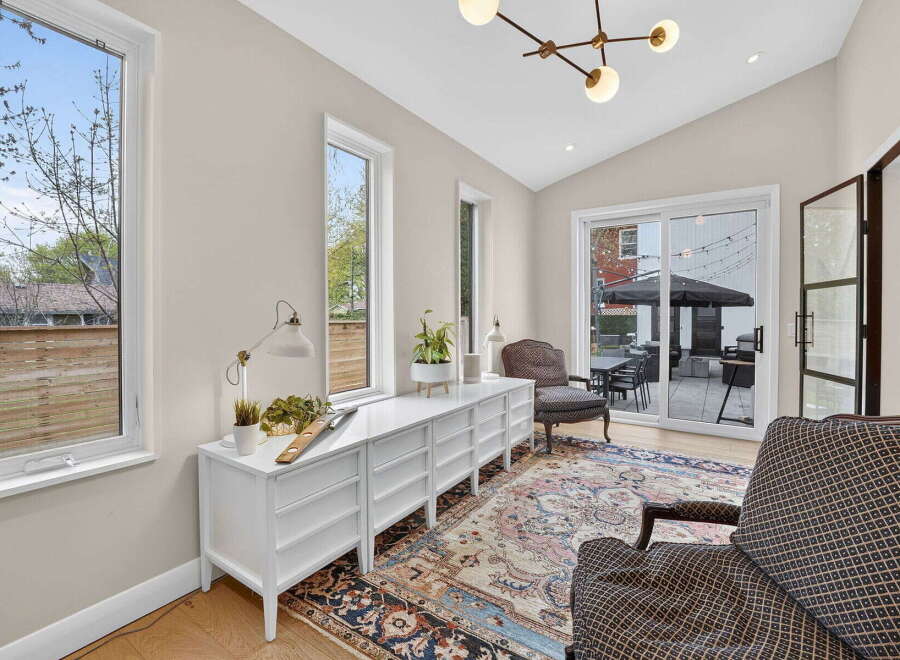 Step into this bright and airy living space, featuring a stylish white dresser and elegant armchairs.