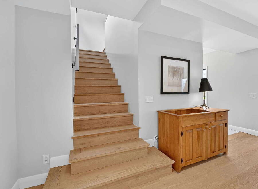 This stunning property features a beautifully crafted staircase with natural wood steps, creating a warm and inviting atmosphere.