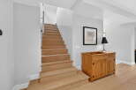 This stunning property features a beautifully crafted staircase with natural wood steps, creating a warm and inviting atmosphere.