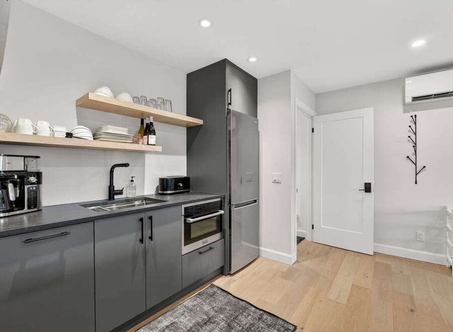 Discover modern living in this stylish kitchen, featuring sleek gray cabinetry and a stainless steel refrigerator.
