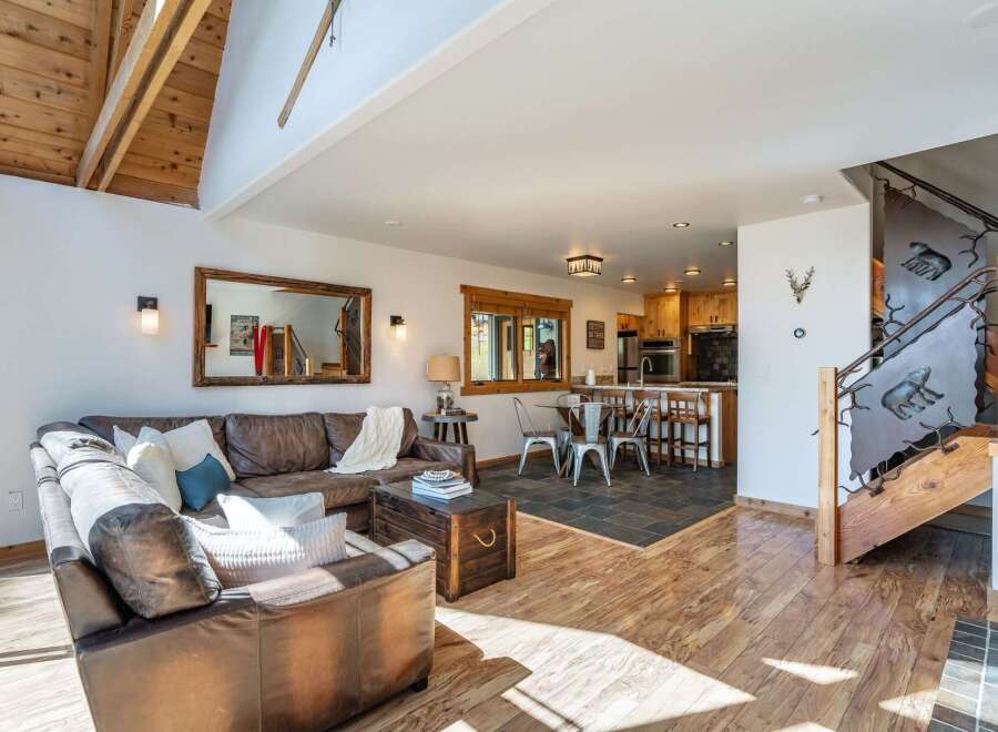 Step into luxury with this stunning property, featuring a spacious living area with a cozy leather sofa and a rustic wooden chest.
