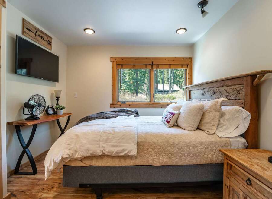 This cozy bedroom features a rustic wooden bed frame and a charming window that offers a scenic view of the surrounding nature.