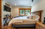 This cozy bedroom features a rustic wooden bed frame and a charming window that offers a scenic view of the surrounding nature.