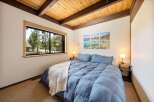 This cozy bedroom features a stunning wooden ceiling and a large window that offers a beautiful view of the surrounding trees.
