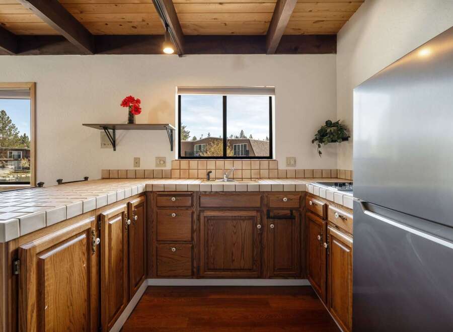 Step into this charming kitchen, featuring warm wooden cabinetry and a tiled countertop.