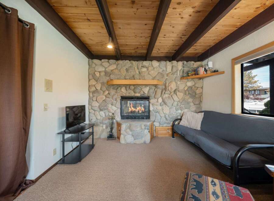This cozy living space features a stunning stone fireplace, perfect for those chilly evenings.